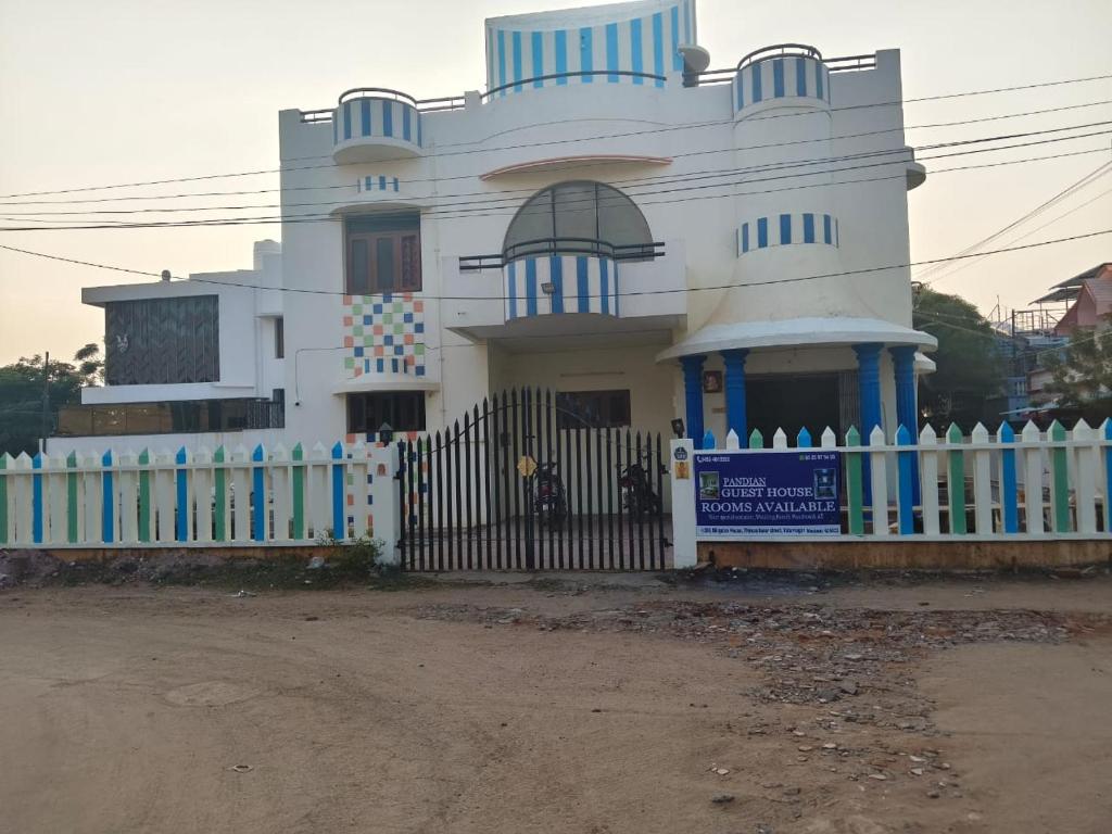 a white house with a fence in front of it at Pandiyan guest house in Madurai