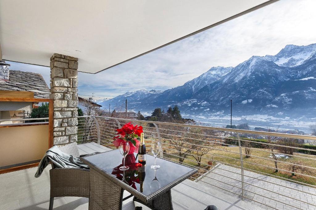 a balcony with a table and a view of mountains at Alpenglow Maison Lugon in Saint-Christophe