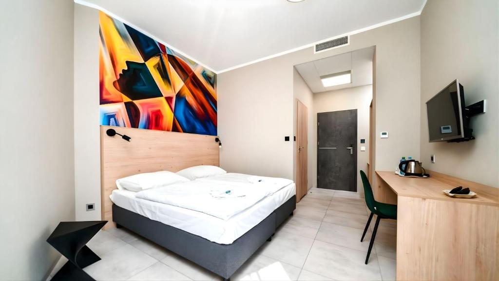 a bedroom with a bed and a desk and a painting at Za Bunkrem 2 0 in Zbrosławice