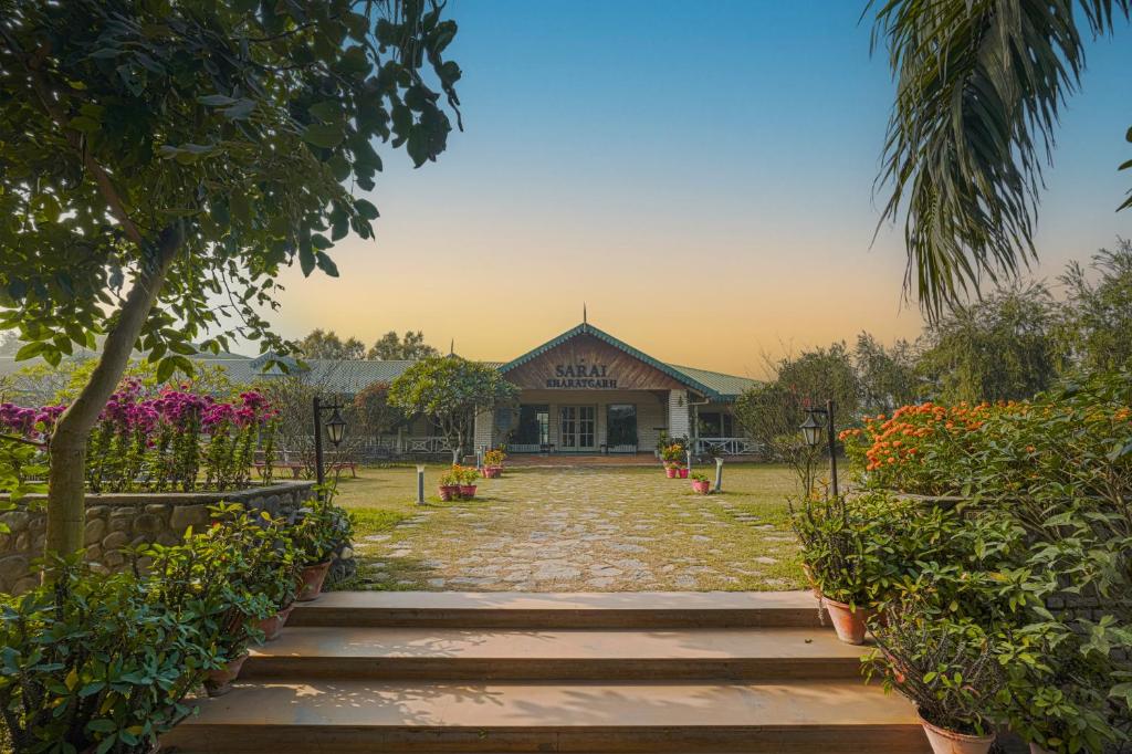 a pathway leading to a building with flowers and plants at Hotel Sarai Bharatgarh in Nohan