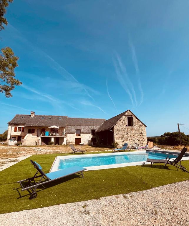 a swimming pool with two chairs and a house at Auberge des Riders in Loze