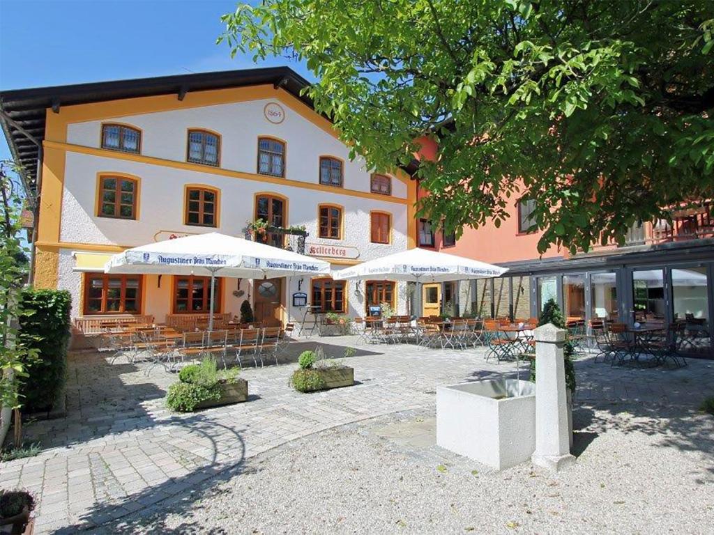 a building with tables and umbrellas in a courtyard at Huberwirt am Kellerberg in Wasserburg am Inn