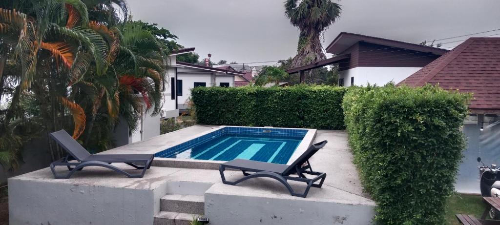a swimming pool with two chairs next to a house at Lucky home in the heart of thongsala in Thong Sala