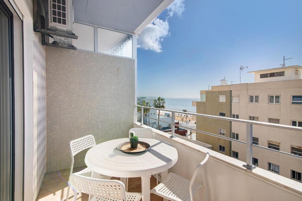 a balcony with a table and chairs and a view of the ocean at Abertura Mar Zen in Quarteira