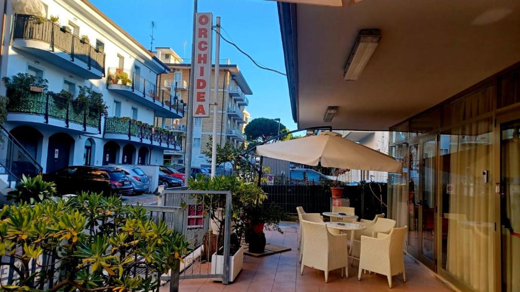 a patio with a table and chairs and an umbrella at Hotel Orchidea Rimini in Rimini