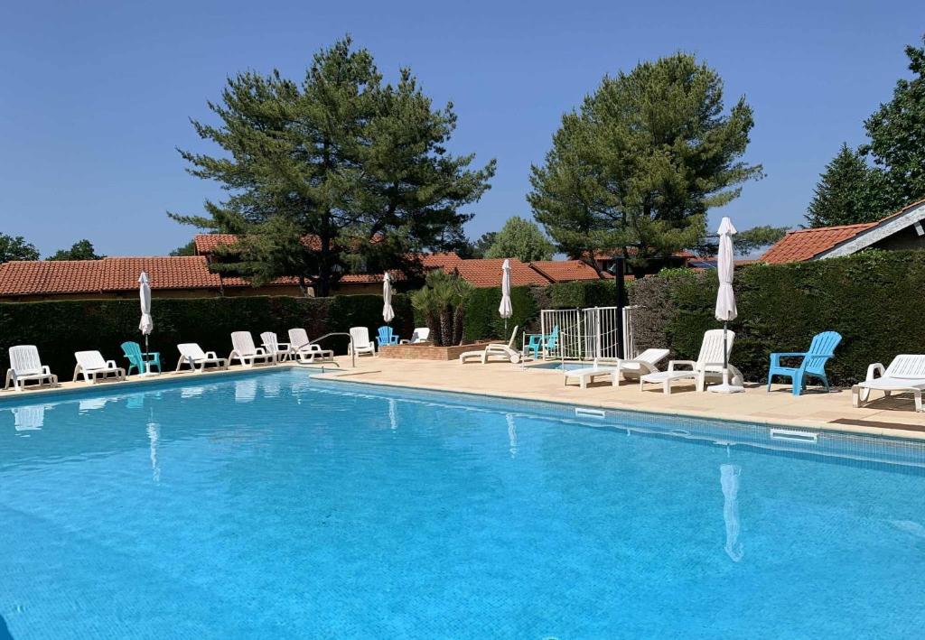 a large swimming pool with chairs and chairs at Les Genêts Studio & Piscine in Eugénie-les-Bains