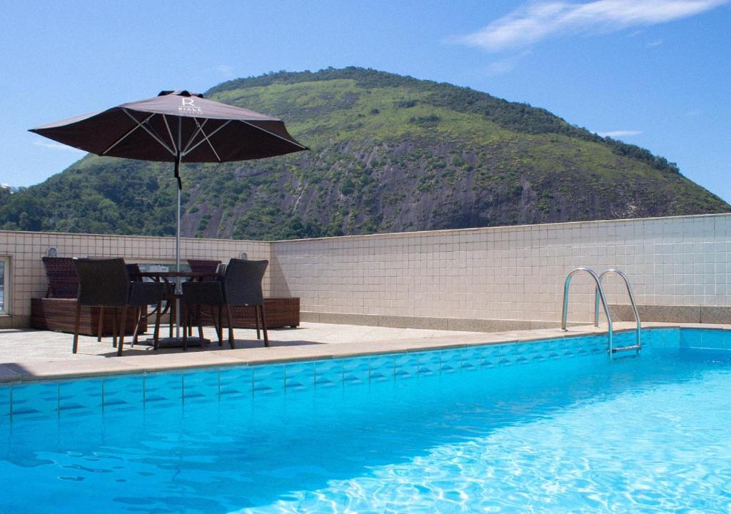 a table with an umbrella next to a swimming pool at Riale Vilamar Copacabana in Rio de Janeiro