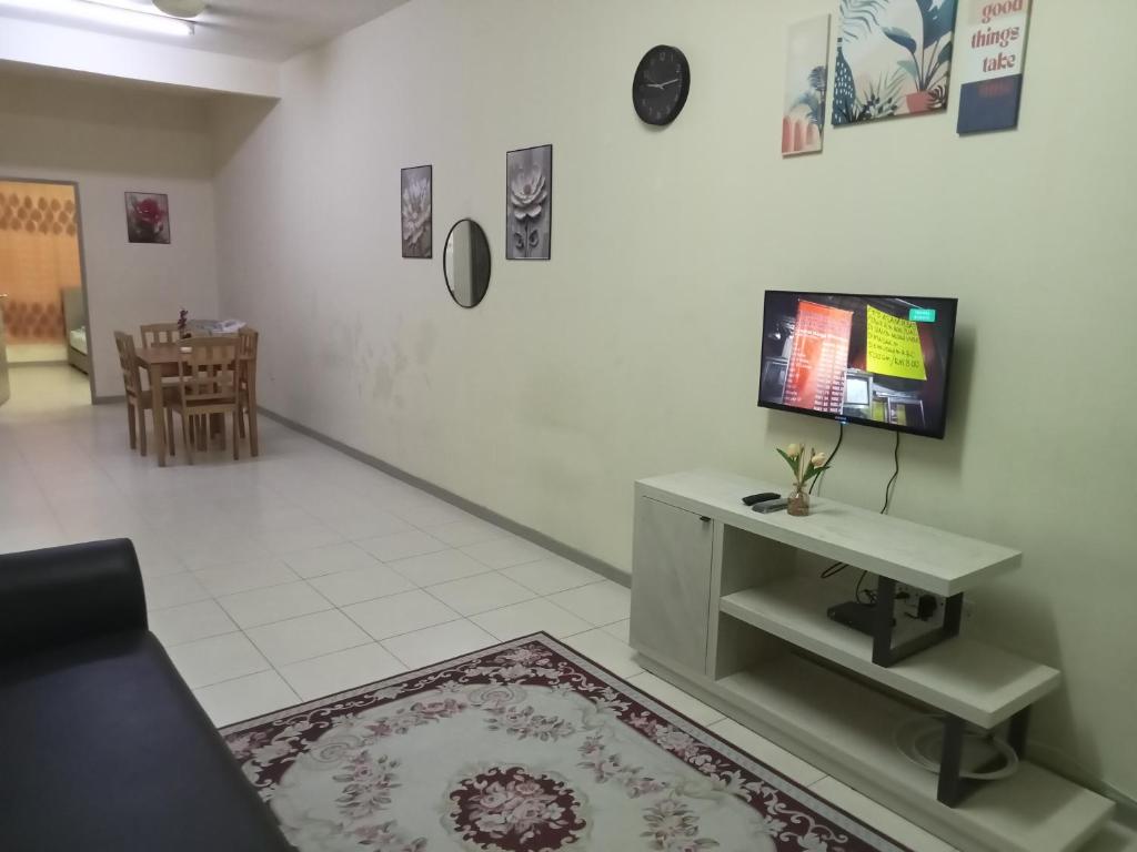 a living room with a table and a tv on a wall at Ayyash Cozy Homestay in Kuala Lipis