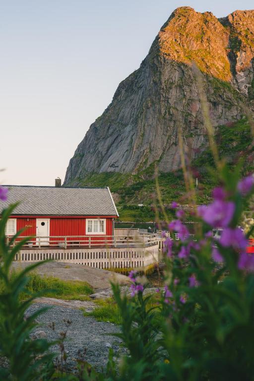 a red building with a mountain in the background at Maybua by May's in Reine