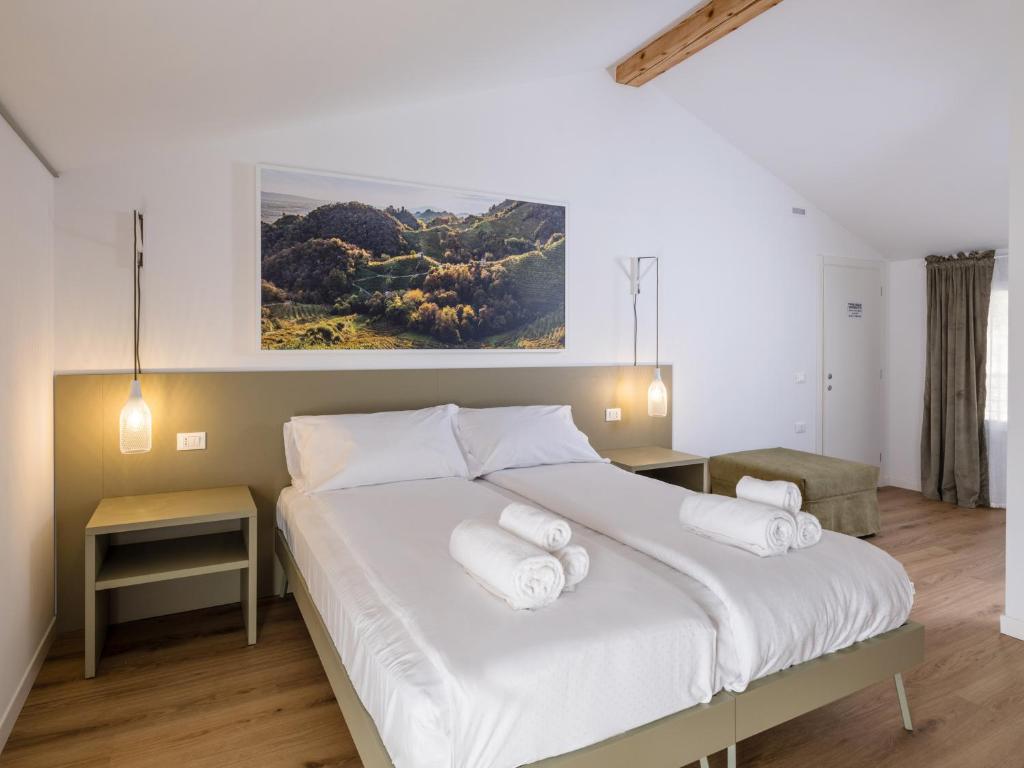 a bedroom with a large white bed with three pillows at Lambo Cellini - Bed & Breakfast in Valdobbiadene