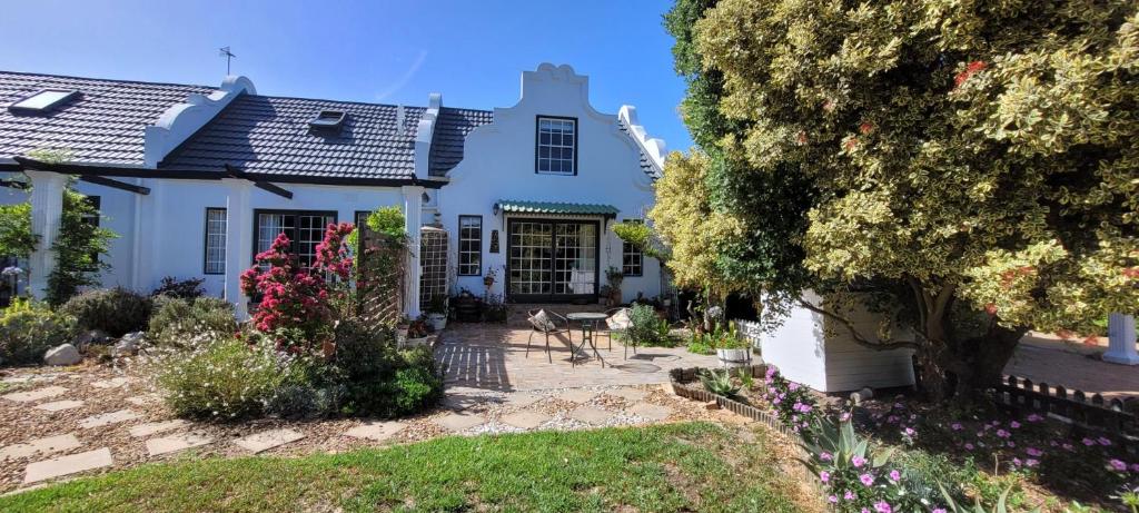 a white house with a garden in front of it at Clarents Cottage in Somerset West