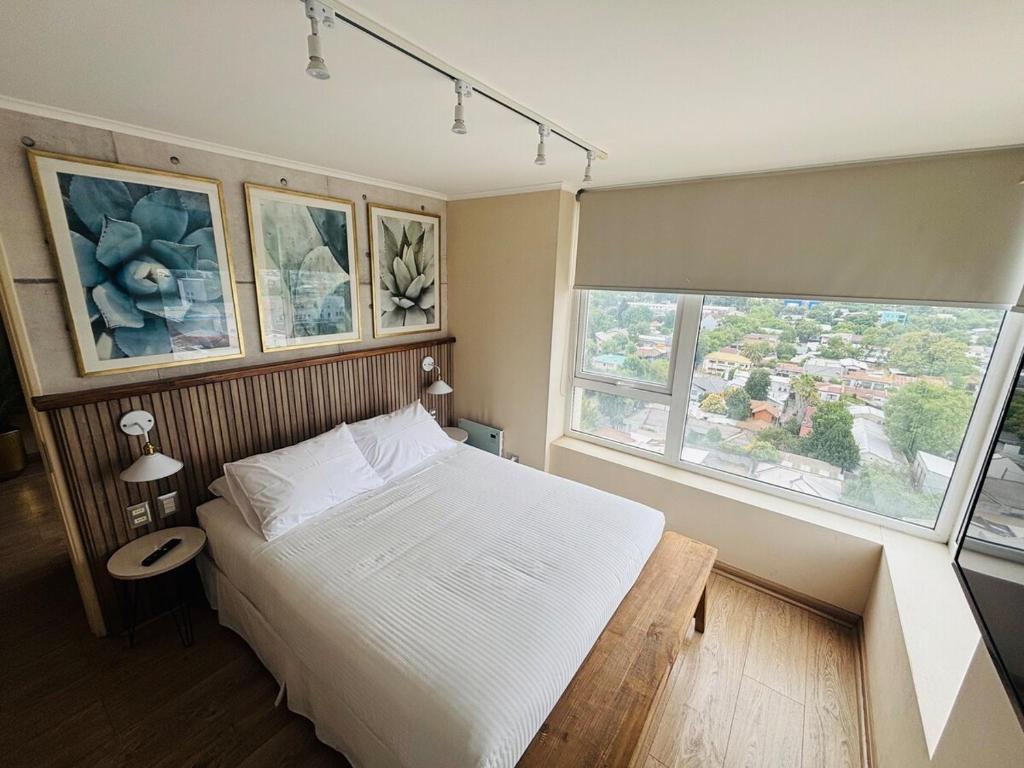 a bedroom with a white bed and two windows at Apart Hotel RCB in Chillán