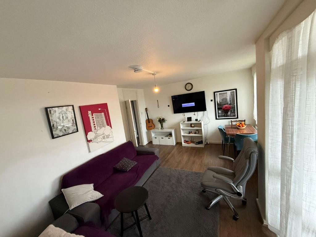 a living room with a purple couch and a table at Birch House in London