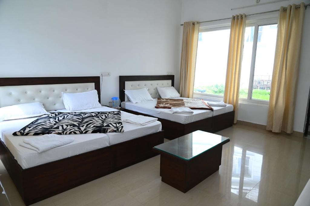 two beds in a room with a window at Ayushman hotel in Uttarkāshi
