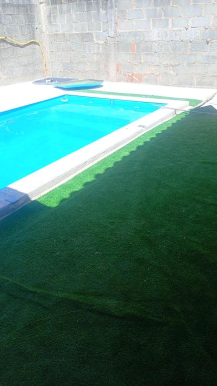 a swimming pool with green grass next to a brick wall at Ambiente familhiar in Guarapari