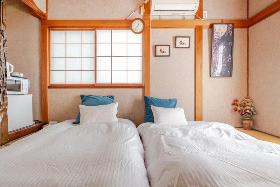 two twin beds in a room with a window at TOMO HOUSE in Taketoyo