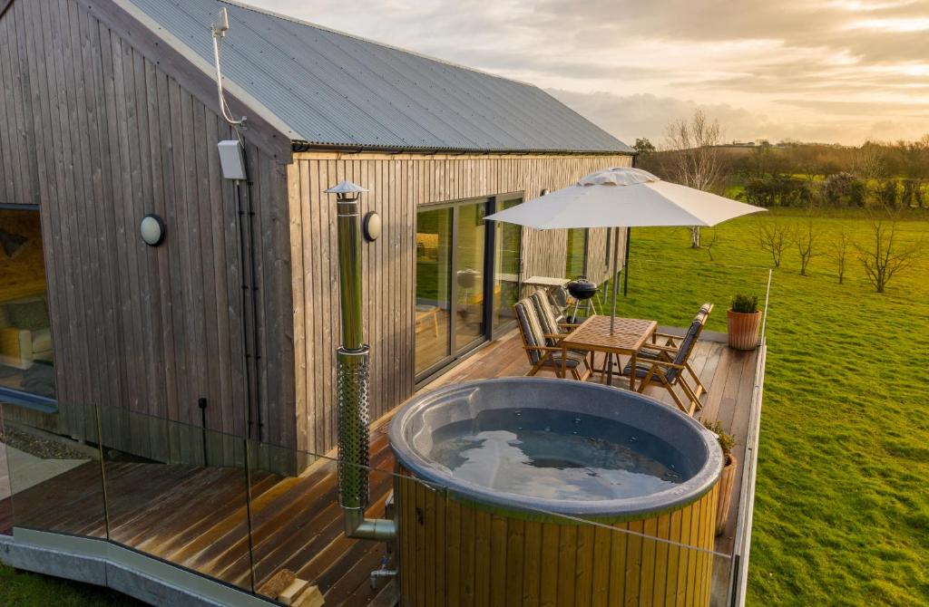 a hot tub on a wooden deck with an umbrella at Willow Lodge Estate in Six Road Ends