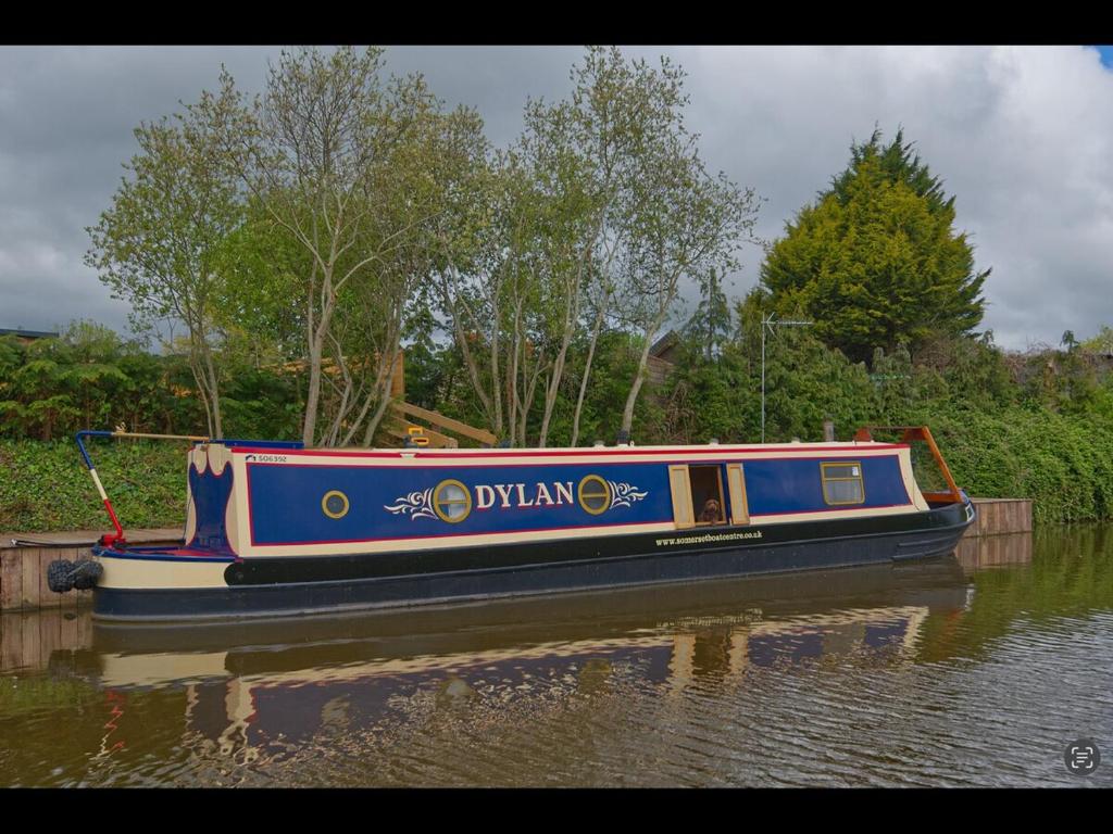 a blue boat in the water on a river at Dylan, 43ft Narrowboat with Garden in North Newton