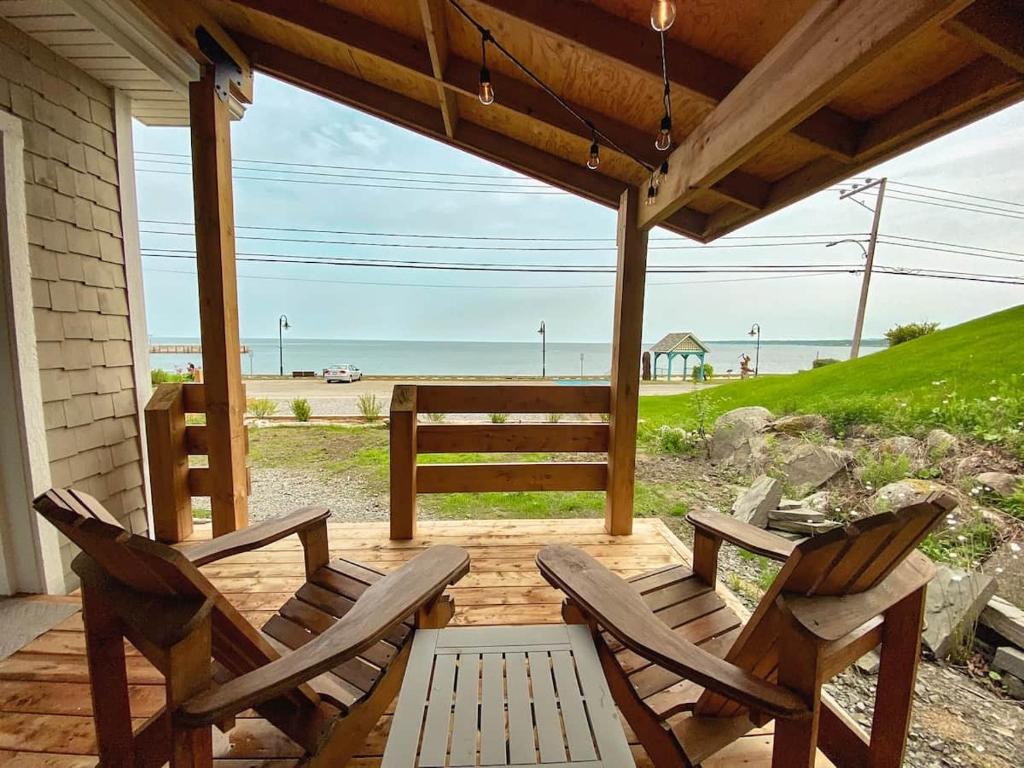 two chairs and a table on a porch with the beach at Couette et Marées - Maisonnette in Sainte-Luce-sur-Mer