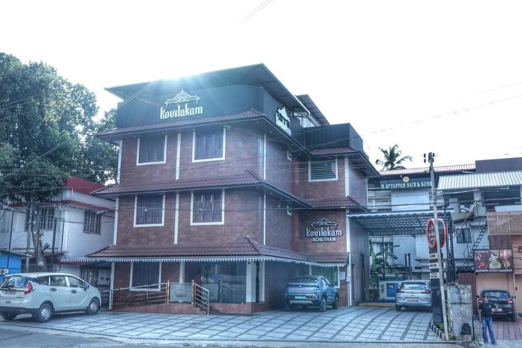 a building with cars parked in front of it at Kovilakam Achutham in Guruvāyūr