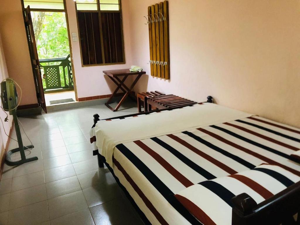a bedroom with a bed with a striped blanket at Terico resort in Belihuloya