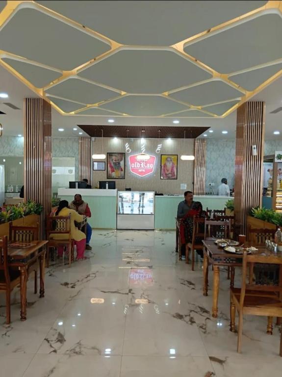 a dining room with people sitting at tables in a restaurant at Old RAO Hotel Kotwan in Kosi