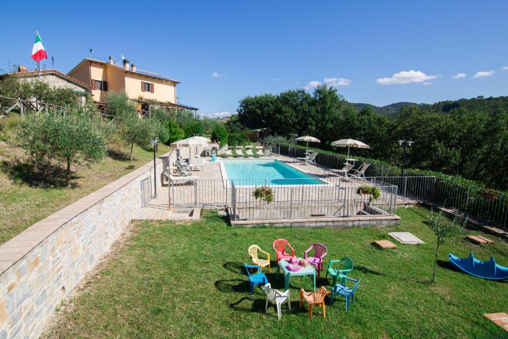 a backyard with a swimming pool and chairs and a table at Agriturismo La Coccinella in Valfabbrica