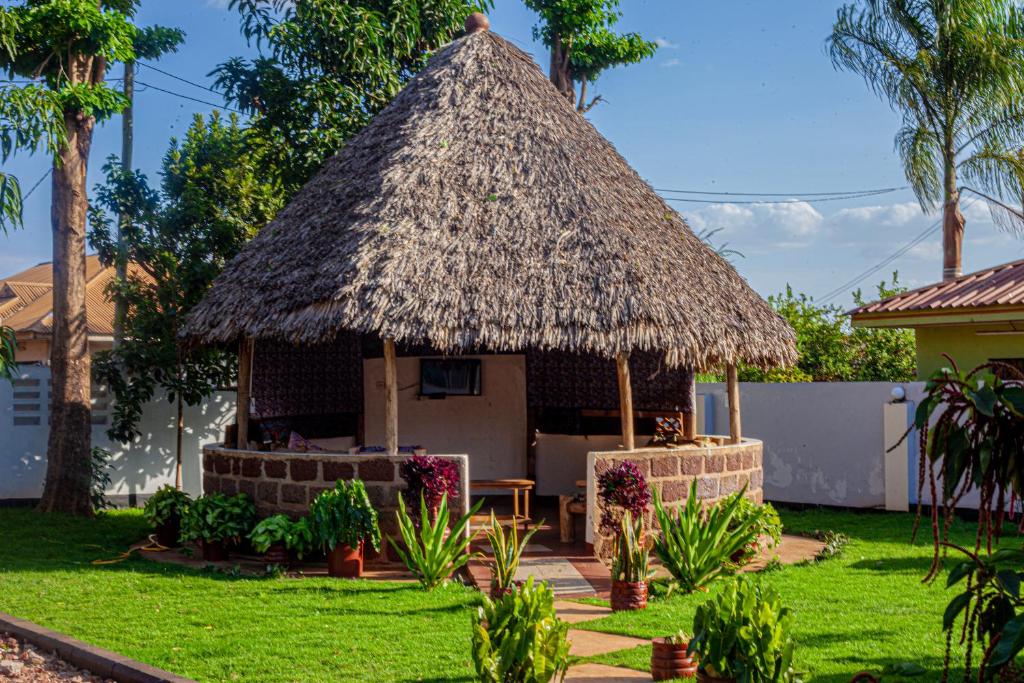 a hut with a grass roof in a yard at Sisama Lodge in Msaranga
