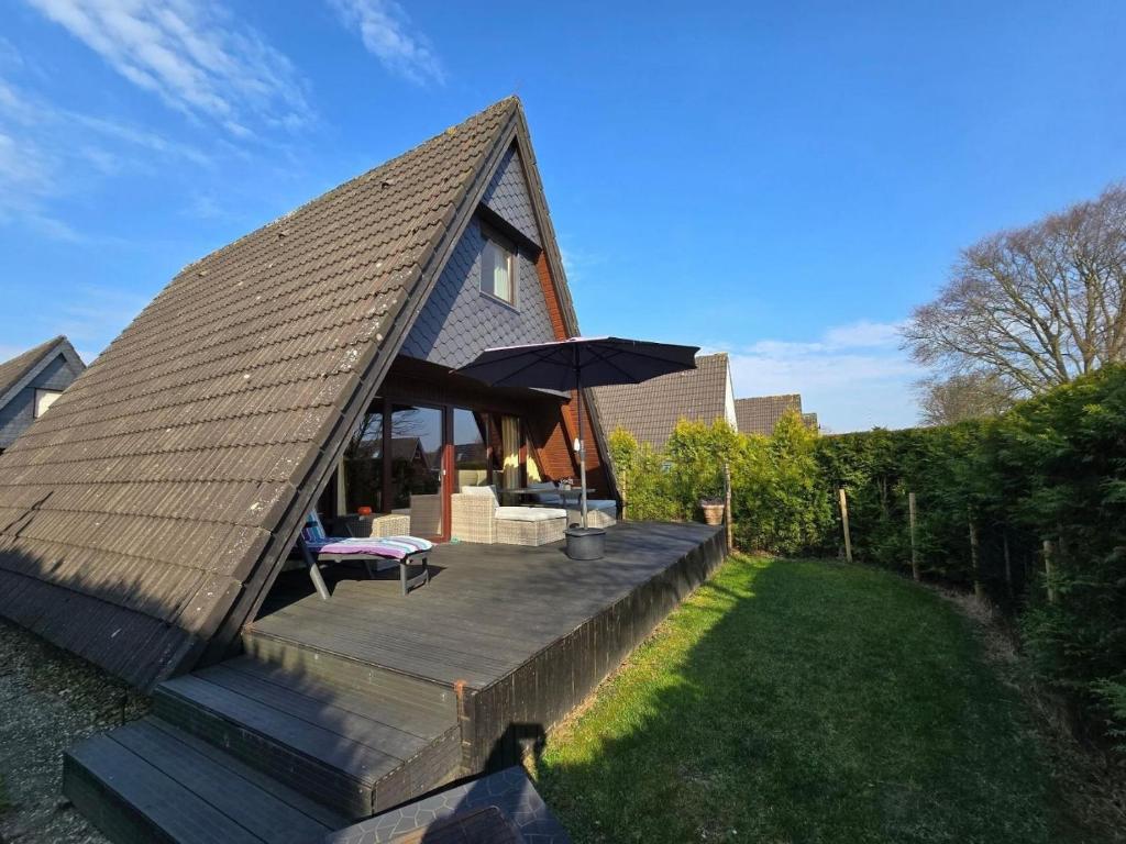 a small house with a roof with a wooden deck at Haus Stern Carolinensiel in Carolinensiel