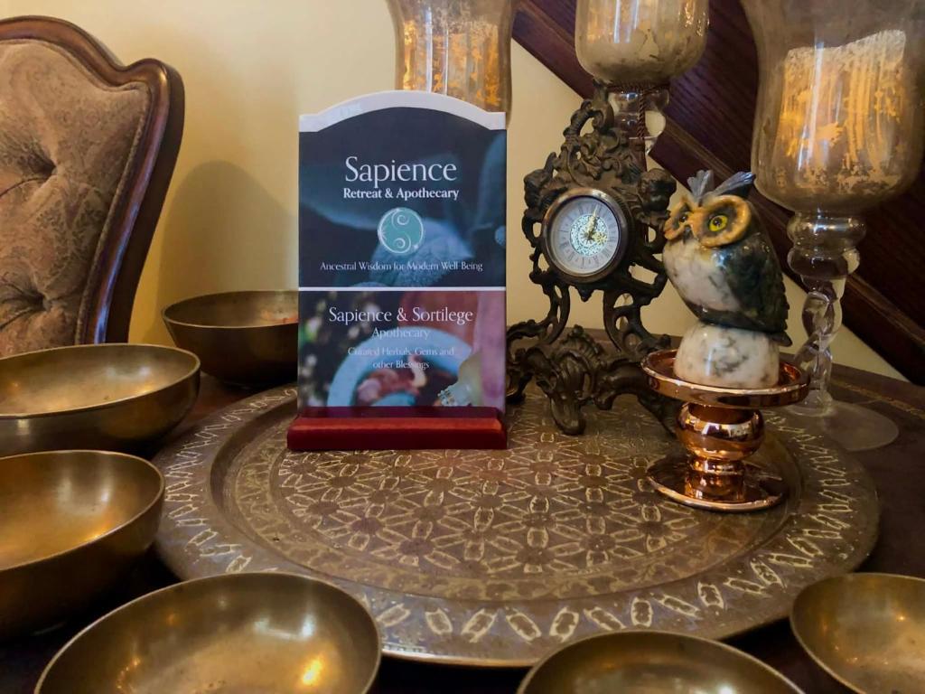 a table with a book and a clock on it at Sapience Retreat & Apothecary in Niagara-on-the-Lake