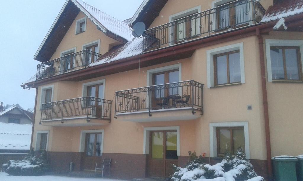 un bâtiment avec balcon et neige au sol dans l'établissement Willa na Skarpie, à Kluszkowce