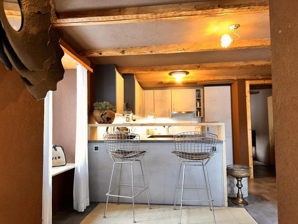 a kitchen with two bar stools and a counter at Revier beau jardin in Glarus