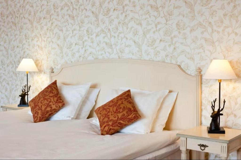 a bedroom with a white bed with two lamps at Mockelsnas Herrgard in Diö
