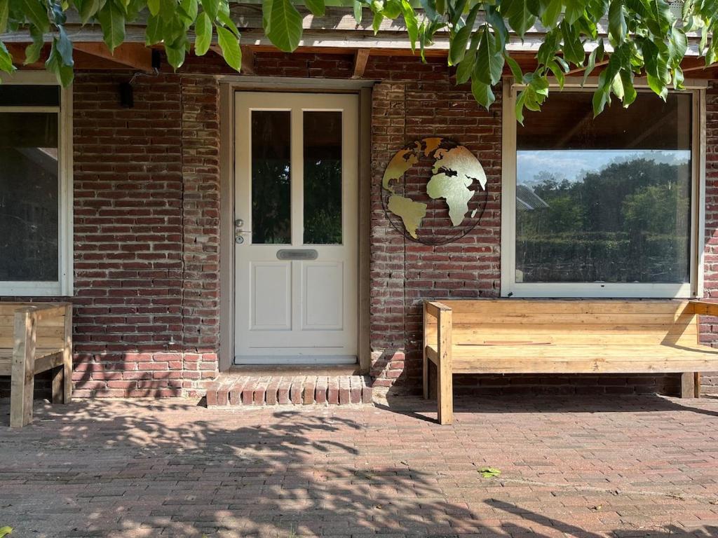 a brick house with a door and two benches at Lucky luke's hideaway in Heibloem