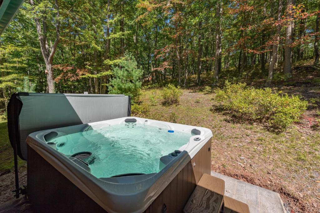 a jacuzzi tub sitting on a deck in the woods at Tranquil Timber by Railey Vacations in Swanton