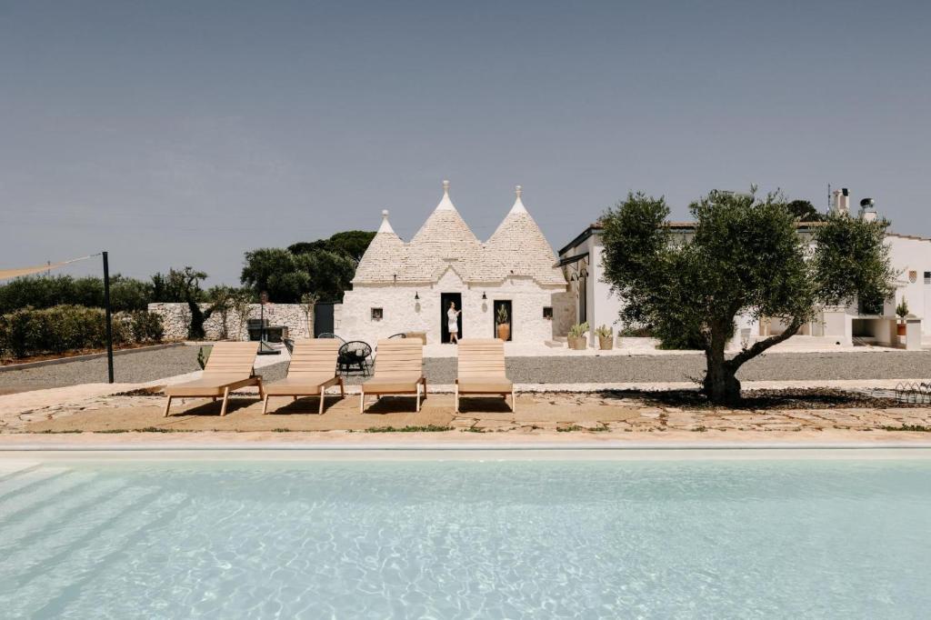 a group of chairs and a house with a pool at Trulli Enjoy in Noci
