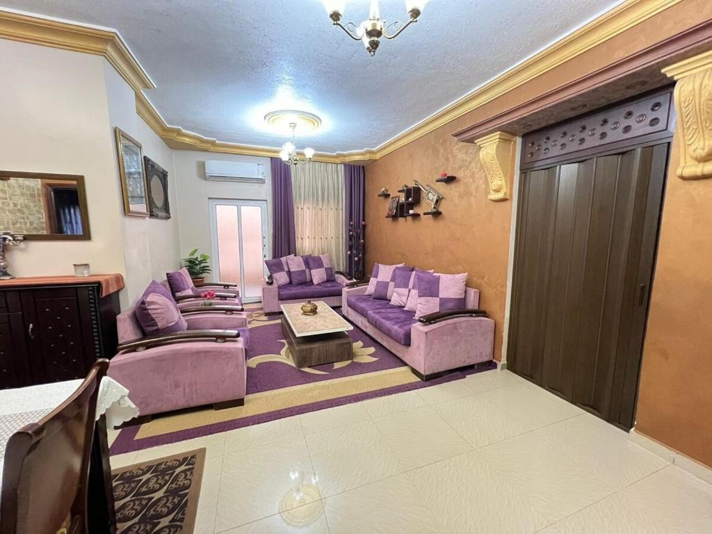 a living room with purple furniture and a sliding door at Jad Apartment in irbid in Irbid