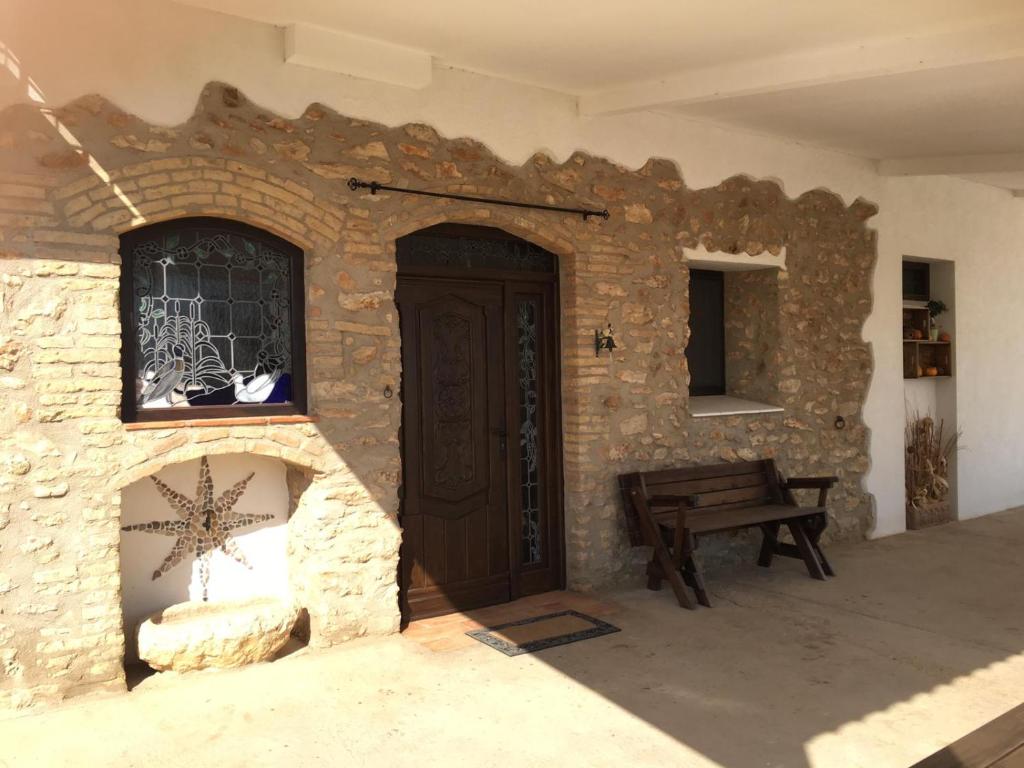 a stone building with a wooden door and a bench at La iaia Merce in L'Aldea