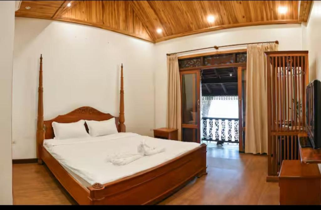 a bedroom with a large bed with a wooden headboard at Colonial House Mekong River View in Luang Prabang