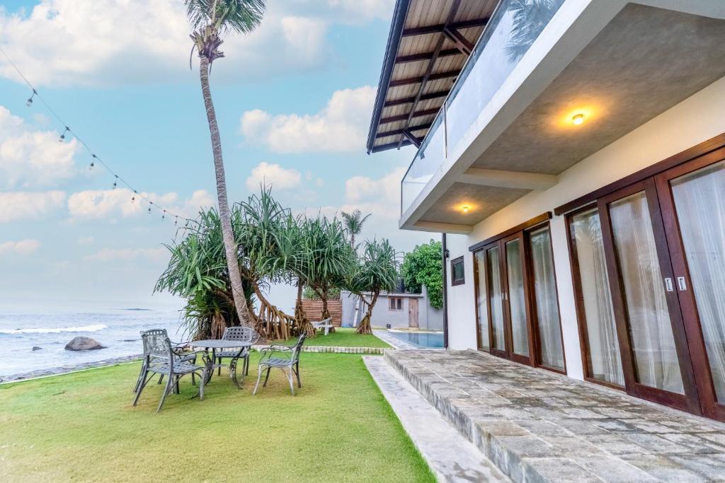 a house with a patio with a table and chairs at Surfside Serenity - SS Beach in Ahangama