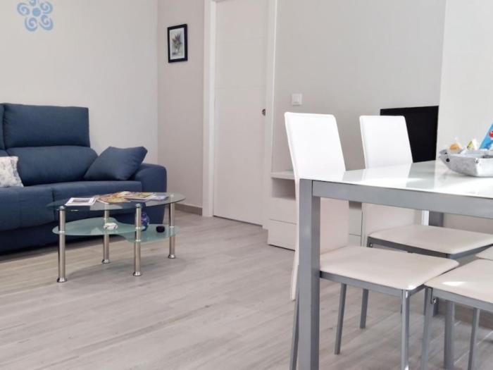 a living room with a blue couch and a table and chairs at Apartamentos los Acantilados Nº 1 Cobreces in Cóbreces