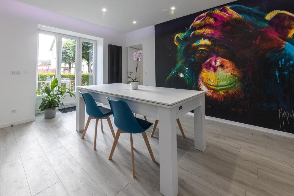 a white table and chairs in a room with a painting at L'Évolution, 1 suite et jardin privé in Vesoul