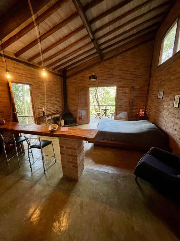 a large room with a bed and a large wooden table at Chalé nas Árvores -Pitayas Agroturismo in Joanópolis