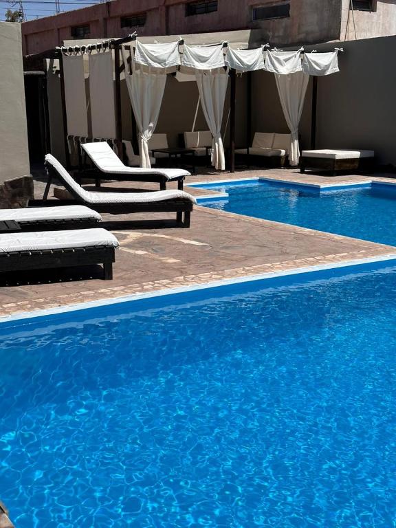 a large swimming pool with chairs and blue water at Casagrande Hotel Boutique in Tinogasta