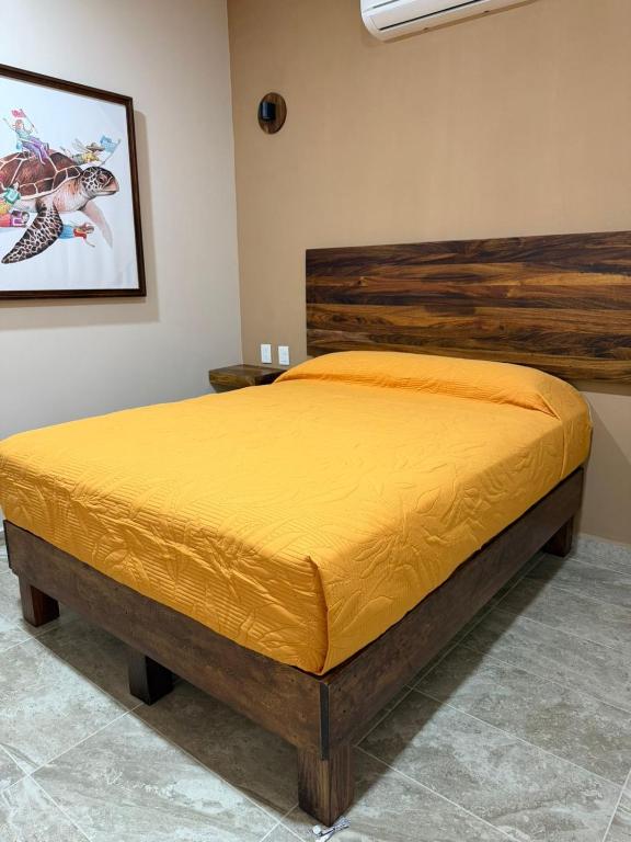 a bedroom with a bed with a yellow bedspread at Hotel Santa Cruz Mazunte in Mazunte