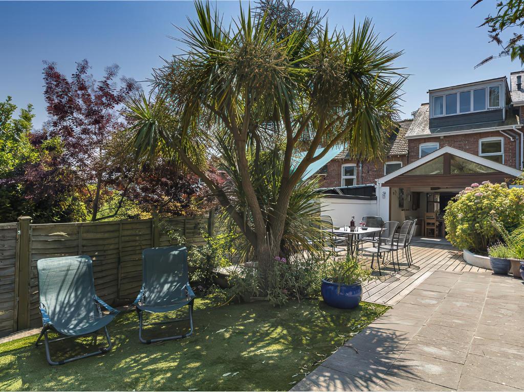 a patio with two chairs and a palm tree at Shipwrights, 11 Coronation Road in Salcombe