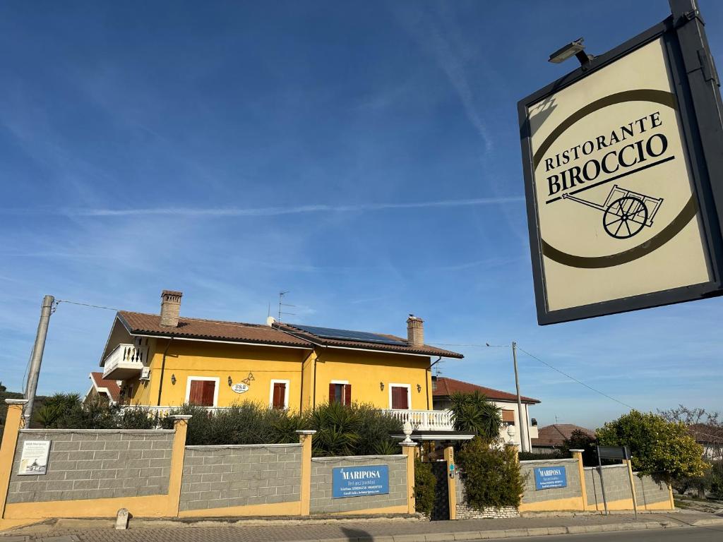 a sign in front of a yellow house at B&B Mariposa in Collecorvino