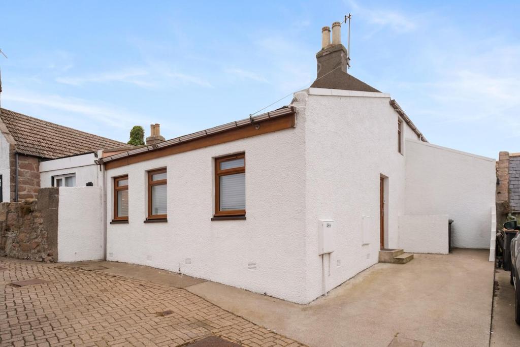 a white house with a driveway in front of it at Creel Cottage, Peterhead in Peterhead