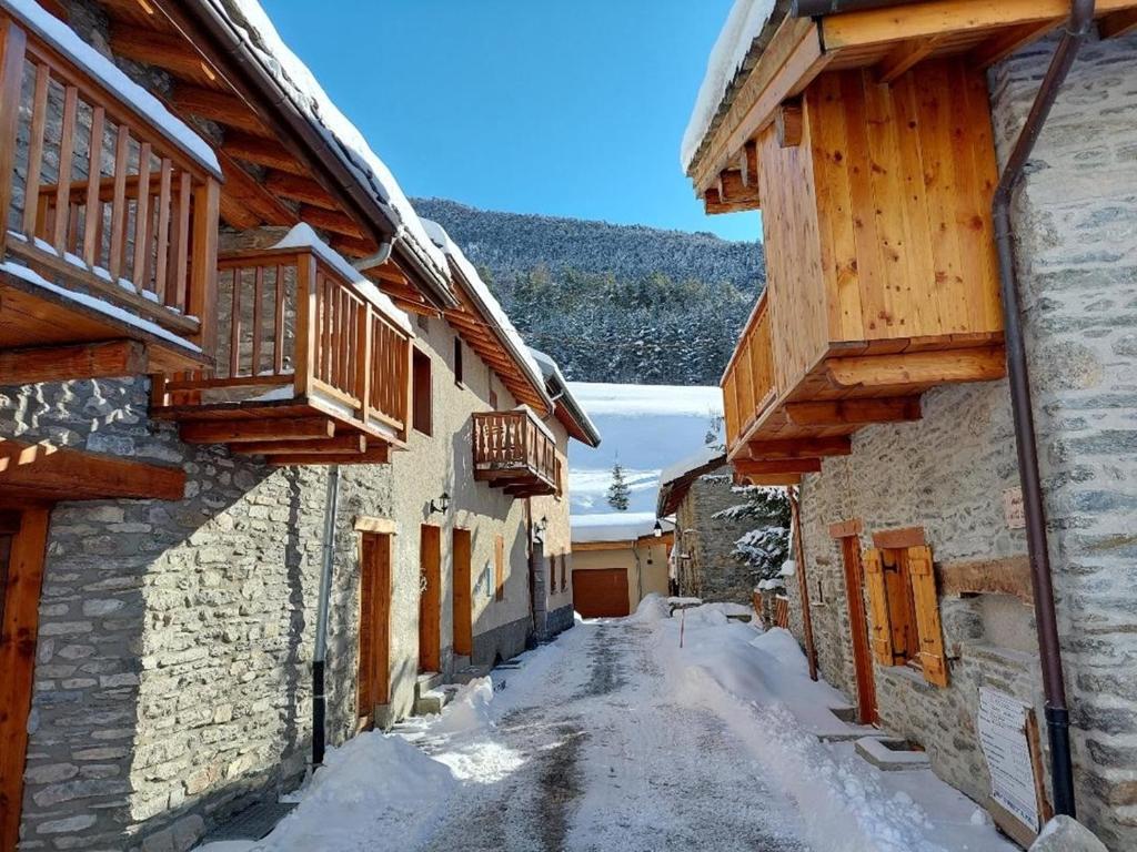 eine verschneite Gasse zwischen zwei Gebäuden mit Holzbalkonen in der Unterkunft Gîte Val Cenis Bramans E I in Bramans