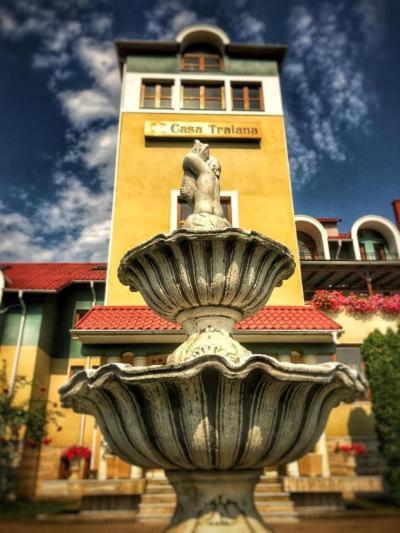 a fountain in front of a building with a tower at Hotel Casa Traiana in Alba Iulia